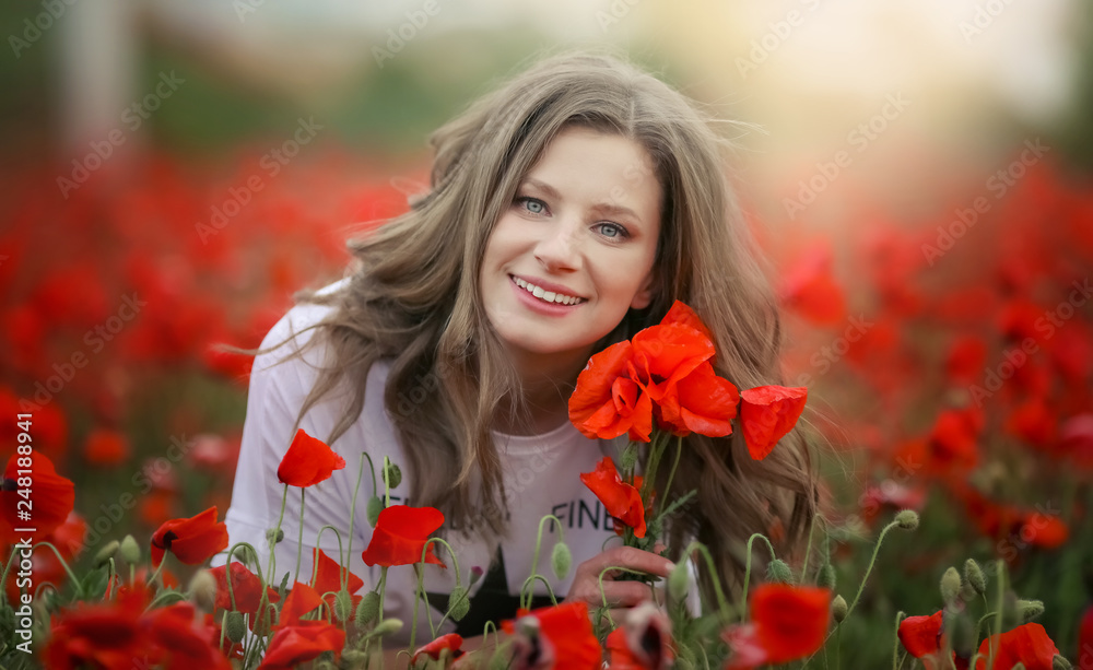 Beautiful happy smiling teen girl portrait with red flowers on head enjoying in poppies field nature background. Makeup and curly hair style. Lifestyle. Beautiful happy smiling teen girl portrait with red flowers on head enjoying in poppies field nature background. Makeup and curly hair style. Lifestyle.