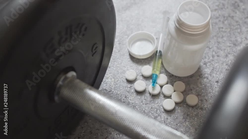 White steroid pills and syringe with dumbbell - doping in sport photo
