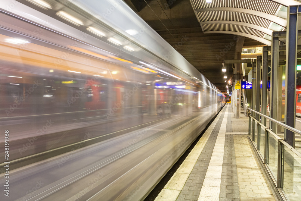 Vorbeifahrender weißer Zug an einem Bahnhof in Deutschland mit leerem Bahnsteig Vorbeifahrender weißer Zug an einem Bahnhof in Deutschland mit leerem Bahnsteig