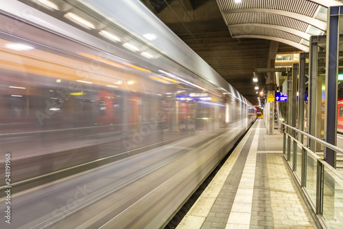 Vorbeifahrender wei  er Zug an einem Bahnhof in Deutschland mit leerem Bahnsteig