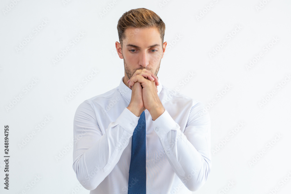 Thoughtful business man thinking hard with his hands clasped Thoughtful business man thinking hard with his hands clasped