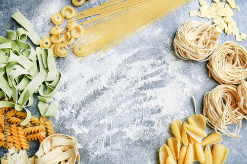 Mixed types and shapes of italian pasta on grey stone background photo