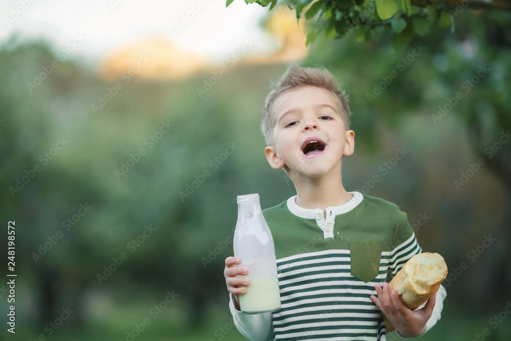 Little boy with girl drink milk and eat a loaf of bread on a haystack in a village at sunset Little boy with girl drink milk and eat a loaf of bread on a haystack in a village at sunset