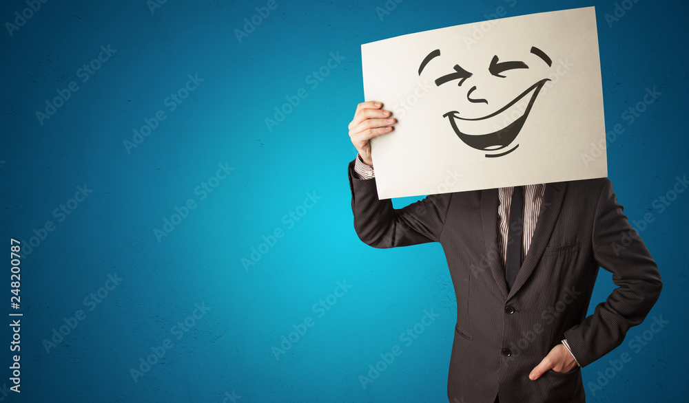 Casual person holding a paper with cool emoticon in front of his face
