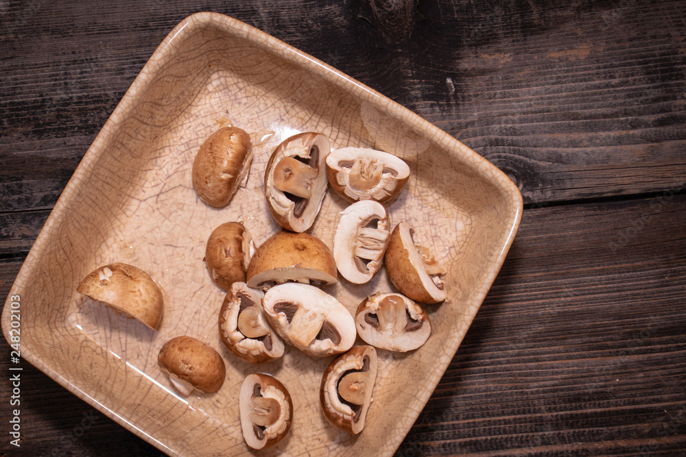 Fototapeta premium Sliced brown champignon mushrooms in a ceramic bowl