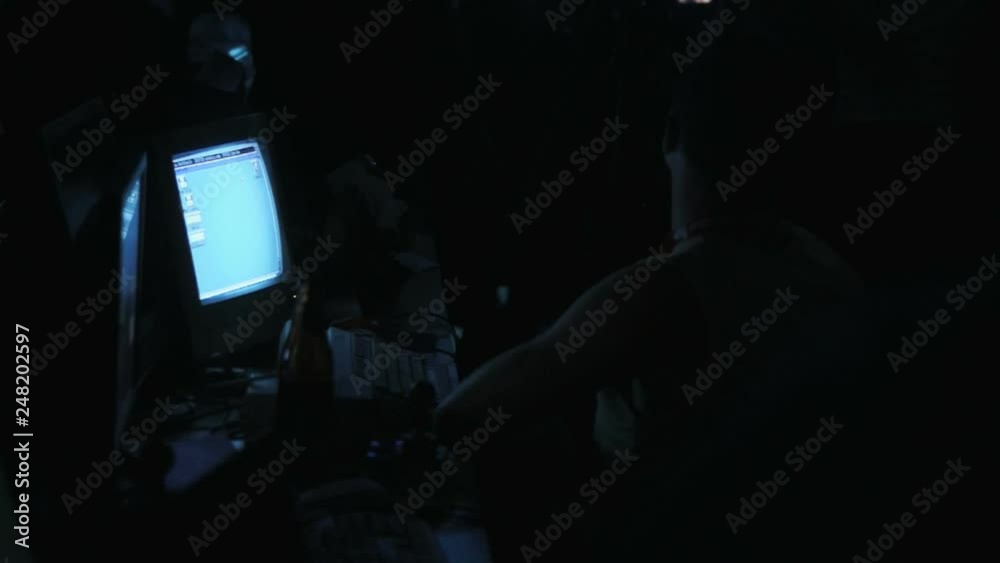 Single man sitting in front of old computer screen in a dark room Single man sitting in front of old computer screen in a dark room