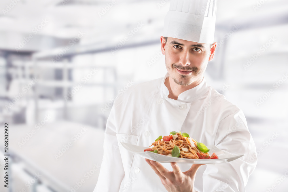 Chef in restaurant kitchen holding plate with italian meal spagh Chef in restaurant kitchen holding plate with italian meal spagh