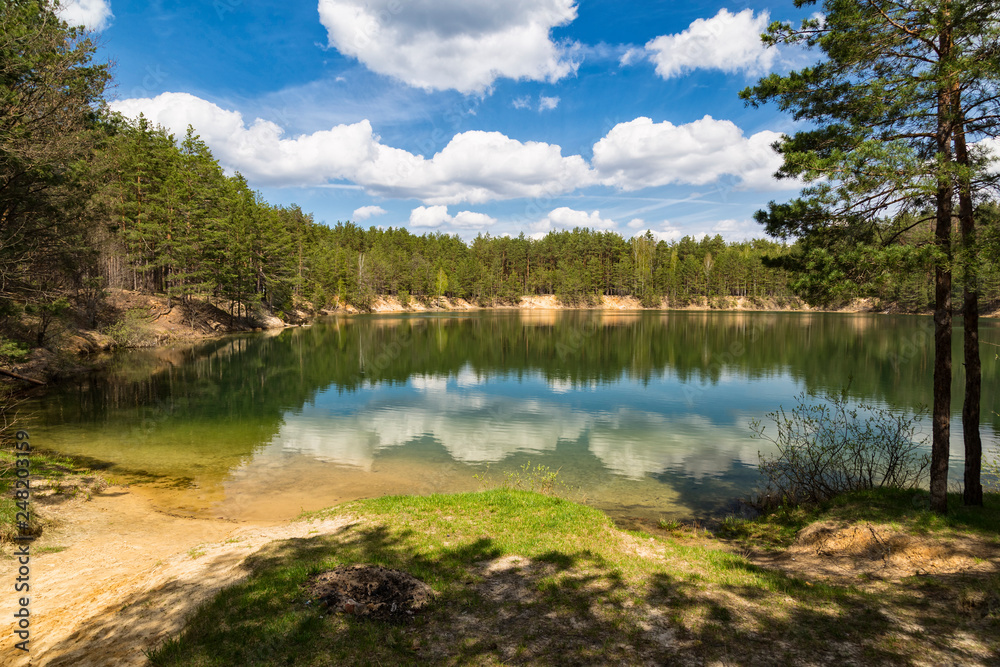 Summer landscape: blue lake surrounded by pine forest Summer landscape: blue lake surrounded by pine forest