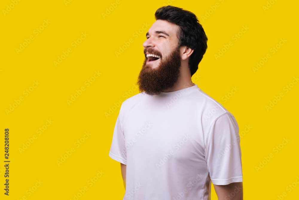 Fototapeta premium Close up portrait of cheerful middle aged man with beard standing and smiling over yellow background