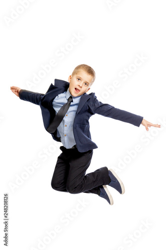 Boy in school uniform jumping, isolated on white background, vertical
