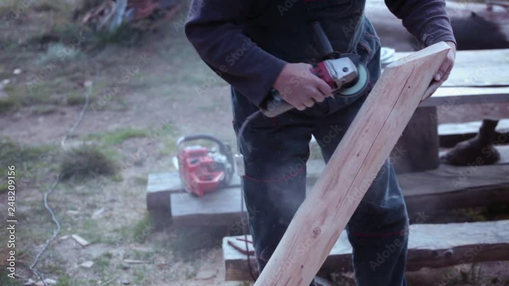 Carpenter polishing dry timber using electric grinder