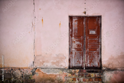 Front of abandoned house with brown wooden  door © Raimonds Kalva
