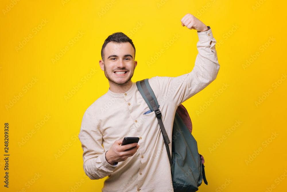 Portrait of happy hansome young man holding his mobile and doing a victory gesture Portrait of happy hansome young man holding his mobile and doing a victory gesture