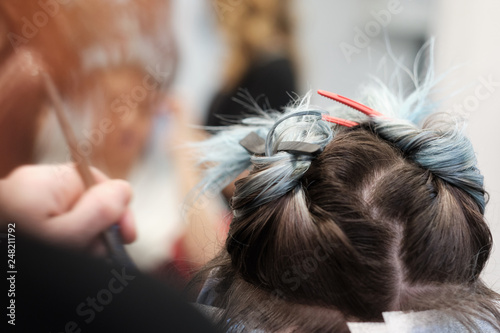 Una mujer recibe el tinte en una peluquería y se ven las manos de la peluquera