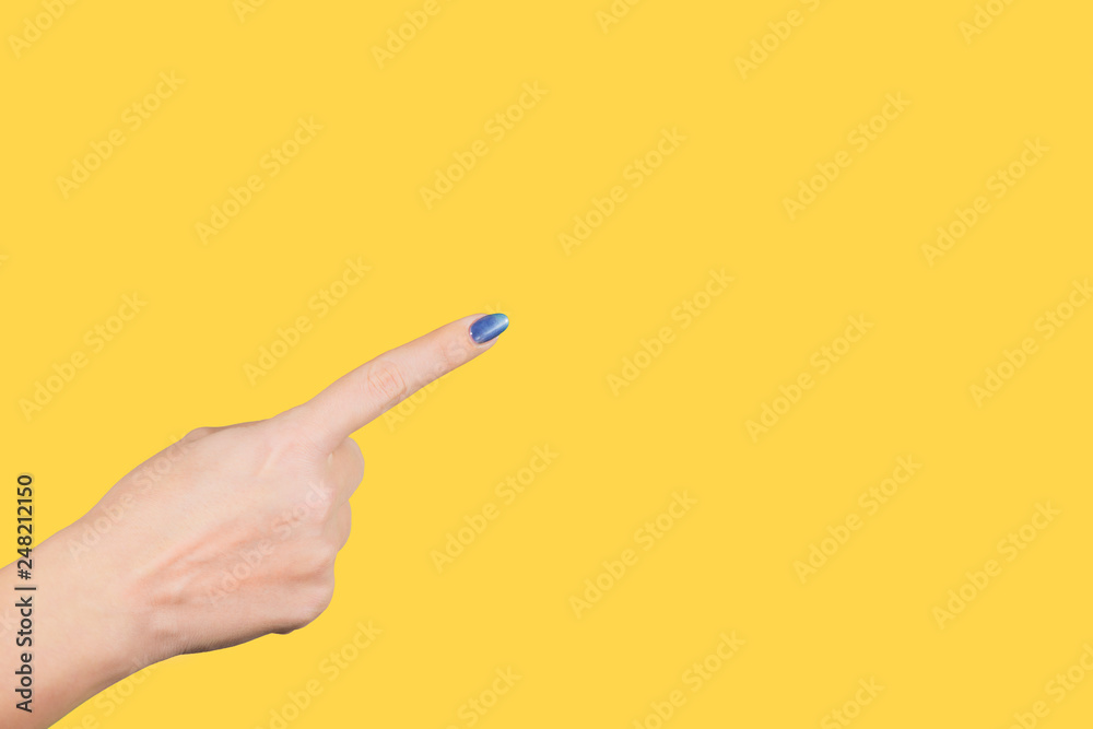 Closeup view of beautiful female hand pointing with her index finger at something virtual and invisible isolated on yellow bright background. Horizontal color photography. Closeup view of beautiful female hand pointing with her index finger at something virtual and invisible isolated on yellow bright background. Horizontal color photography.