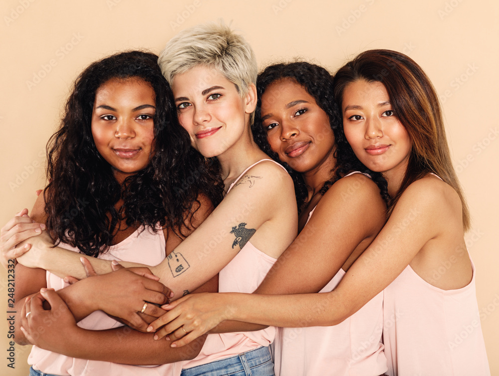 Studio shot of a group of beautiful young women hugging each other - obrazy, fototapety, plakaty 