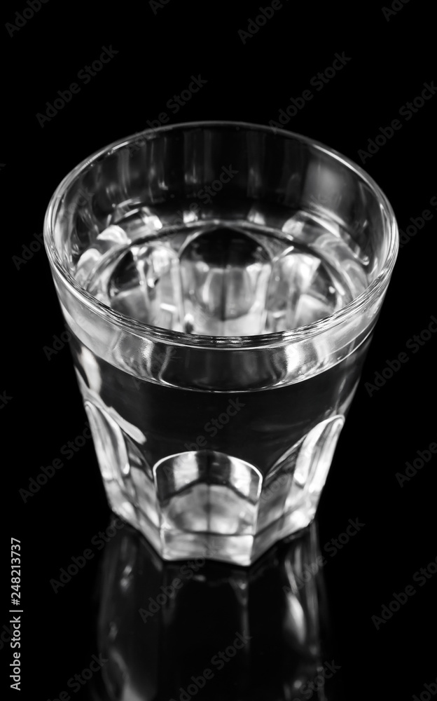 Glass of water on black reflective background. Glass of water on black reflective background.