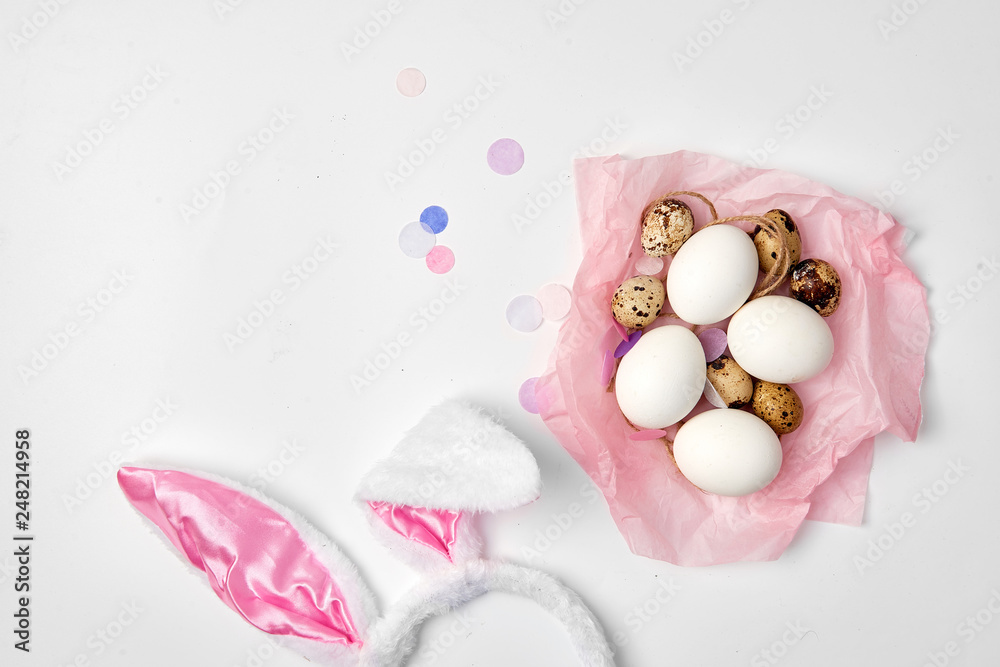 Quail and chicken eggs in a pink paper nest on the white isolated background Easter farm concept copy space