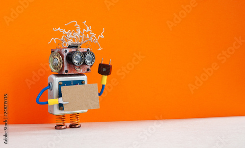 Funny robot with a cardboard card mockup. Creative design robotic toy holding a blank and empty paper poster, orange wall background. copy space for text and design elements
