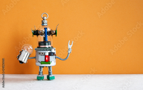 Funny robotic toy holds light bulb. creative design futuristic humanoid robot on brown gray background. copy space