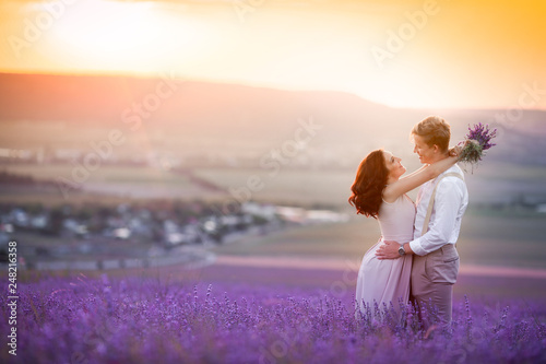 Young couple in love bride and groom, wedding day in summer. Enjoy a moment of happiness and love in a lavender field. Bride in a luxurious wedding dress.