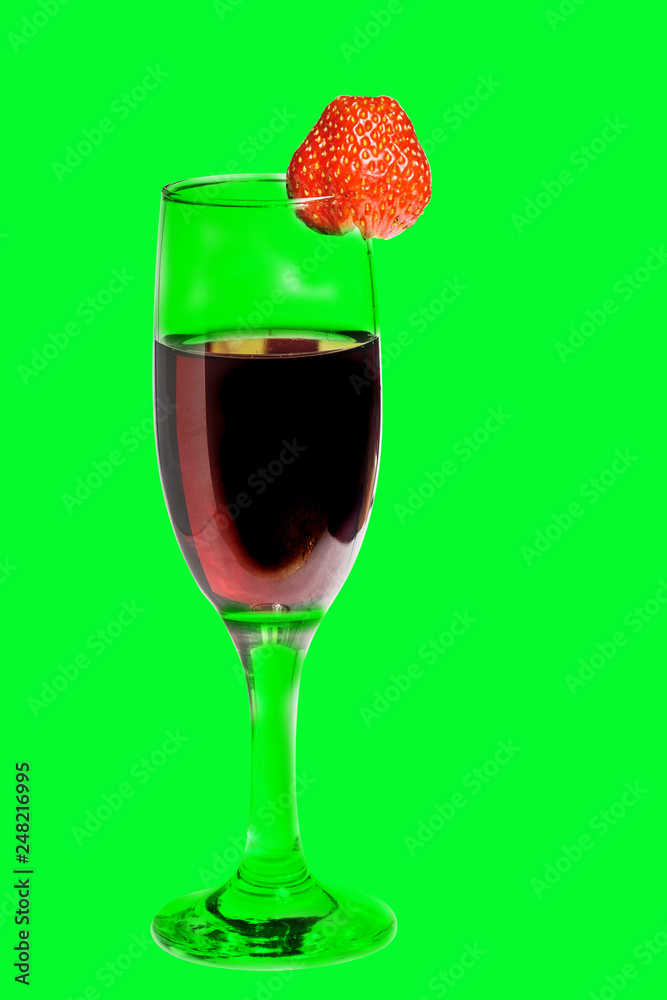 A glass of red homemade wine with strawberries on a green background