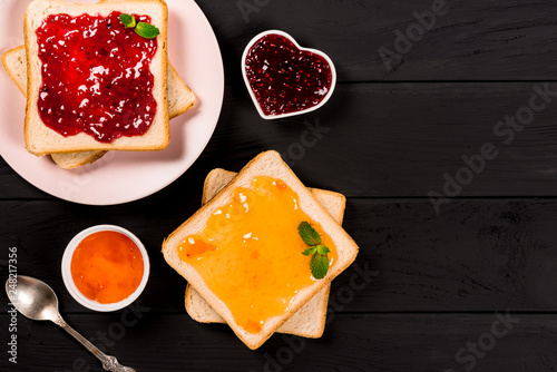 Delicious toasts with various sweet jams on black background. Copyspace for your text, banner.