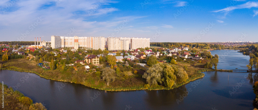 New district with high-rise buildings in the new Moscow on the background of low-rise private sector houses.