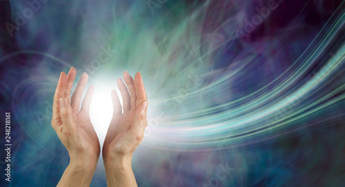 Stunning Healing Energy phenomenon  - pair of hands reaching up into a ball of white  energy with a laser trail and green blue purple ethereal energy field  background