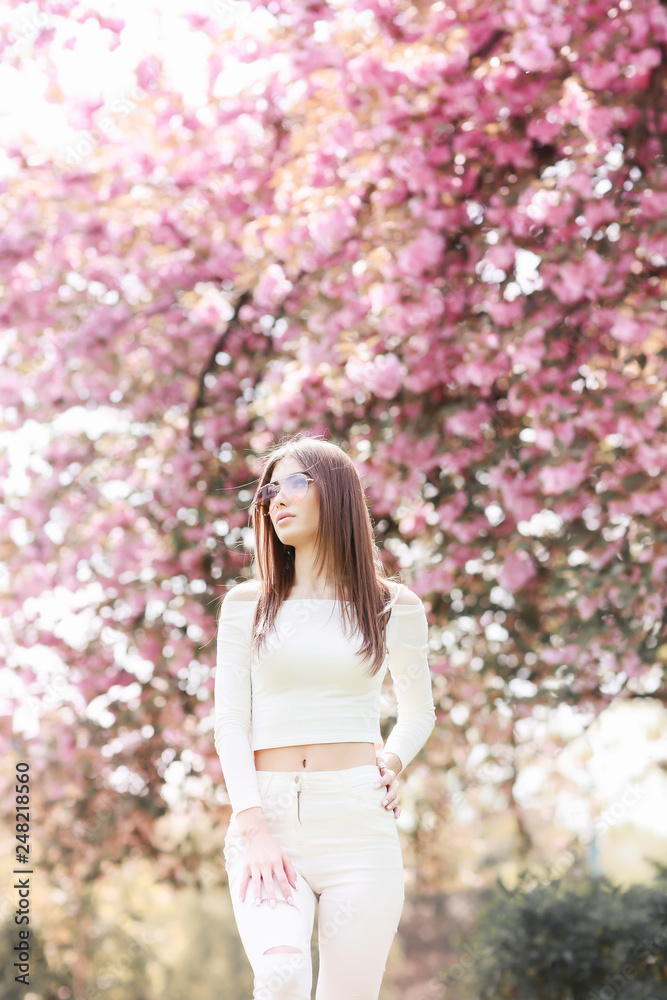Outdoor portrait of young beautiful happy smiling lady posing near flowering tree. Model wearing stylish accessories clothes. Girl closed her eyes. Female beauty fashion concept. City lifestyle. Outdoor portrait of young beautiful happy smiling lady posing near flowering tree. Model wearing stylish accessories clothes. Girl closed her eyes. Female beauty fashion concept. City lifestyle.