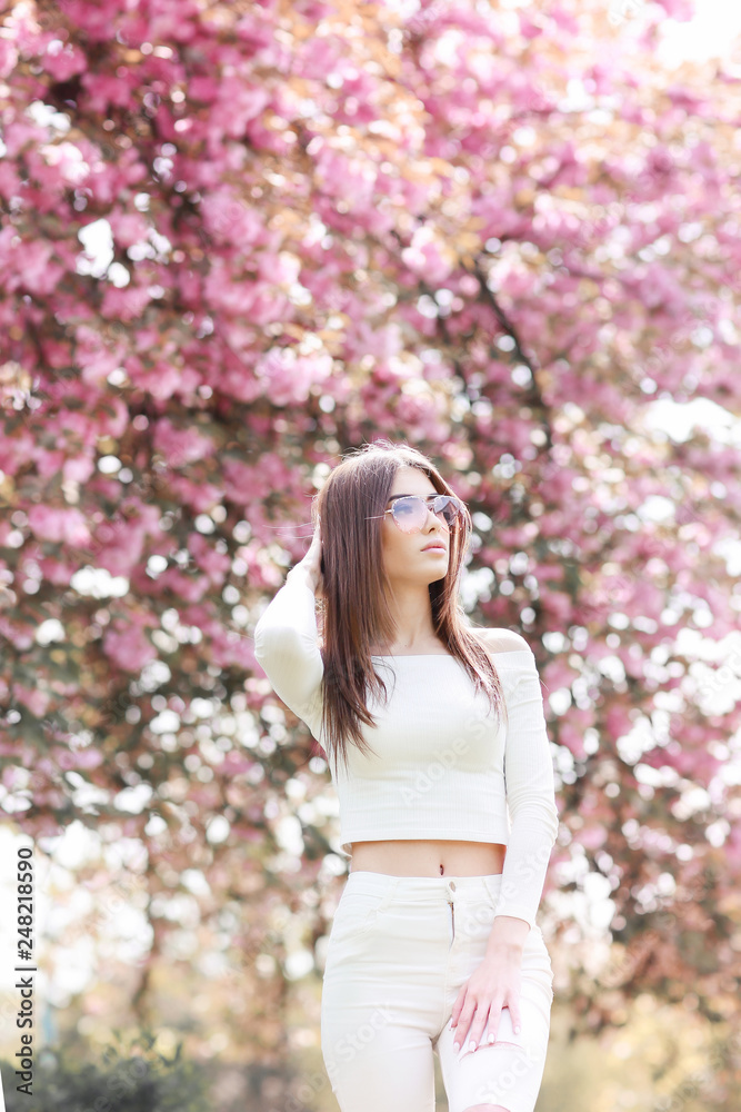 Outdoor portrait of young beautiful happy smiling lady posing near flowering tree. Model wearing stylish accessories clothes. Girl closed her eyes. Female beauty fashion concept. City lifestyle. Outdoor portrait of young beautiful happy smiling lady posing near flowering tree. Model wearing stylish accessories clothes. Girl closed her eyes. Female beauty fashion concept. City lifestyle.