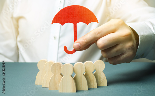 Boss holding a red umbrella and defending his team with a gesture of protection. Life insurance. Customer care, care for employees. Security and safety in a business team. Selective focus