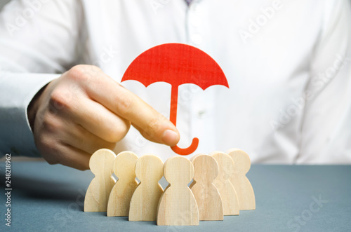 Boss holding a red umbrella and defending his team with a gesture of protection. Life insurance. Customer care, care for employees. Security and safety in a business team. Selective focus photo