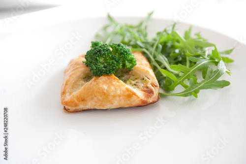 Vegetarian pastry with cheese and broccoli on a white plate