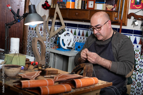 craftsman working the leather in his small saddlery workshop