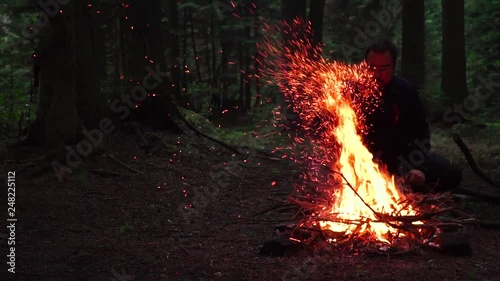 Camper man sitting by the campfire. Sparks emerge from the campfire in slow motion. slow motion image