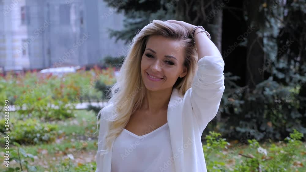 A happy beautiful girl in white suit walking along the street A happy beautiful girl in white suit walking along the street