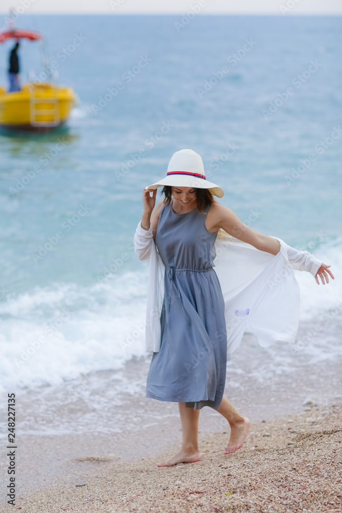 girl wearing a sea cap standing on the beach, clear sky, beautiful sea for relax.