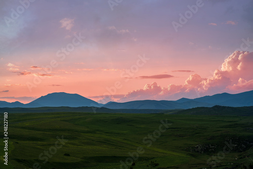 Beautiful sunset over the mountain. Green field. © Inga Av