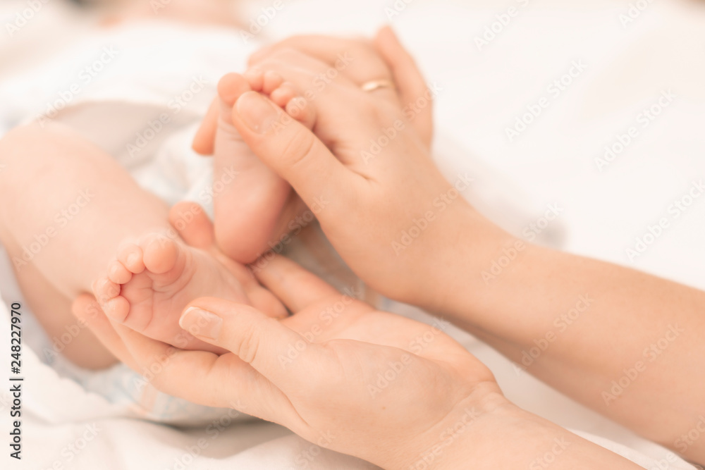 mother's hands gently hold the feet of a newborn baby in the palms mother's hands gently hold the feet of a newborn baby in the palms