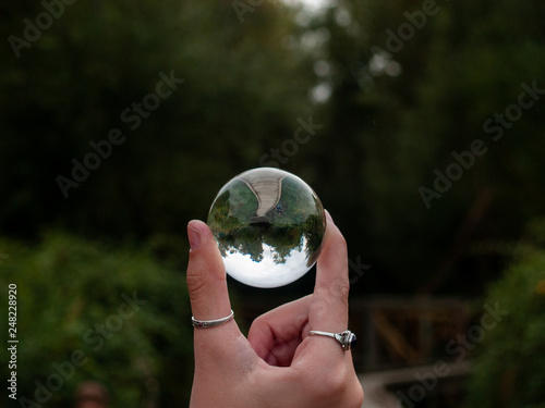 One person with a crystal ball in her hand in a forest in autumn