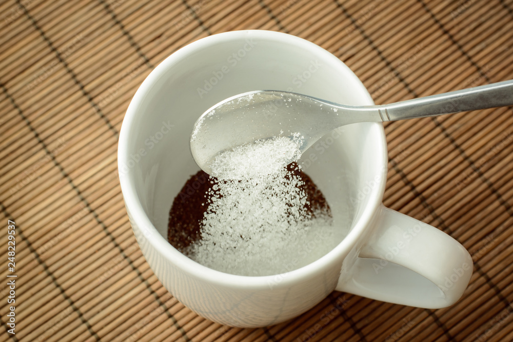 Pouring some sugar to the cup with coffee. Adding sugar to the coffee. Making coffee at home Pouring some sugar to the cup with coffee. Adding sugar to the coffee. Making coffee at home