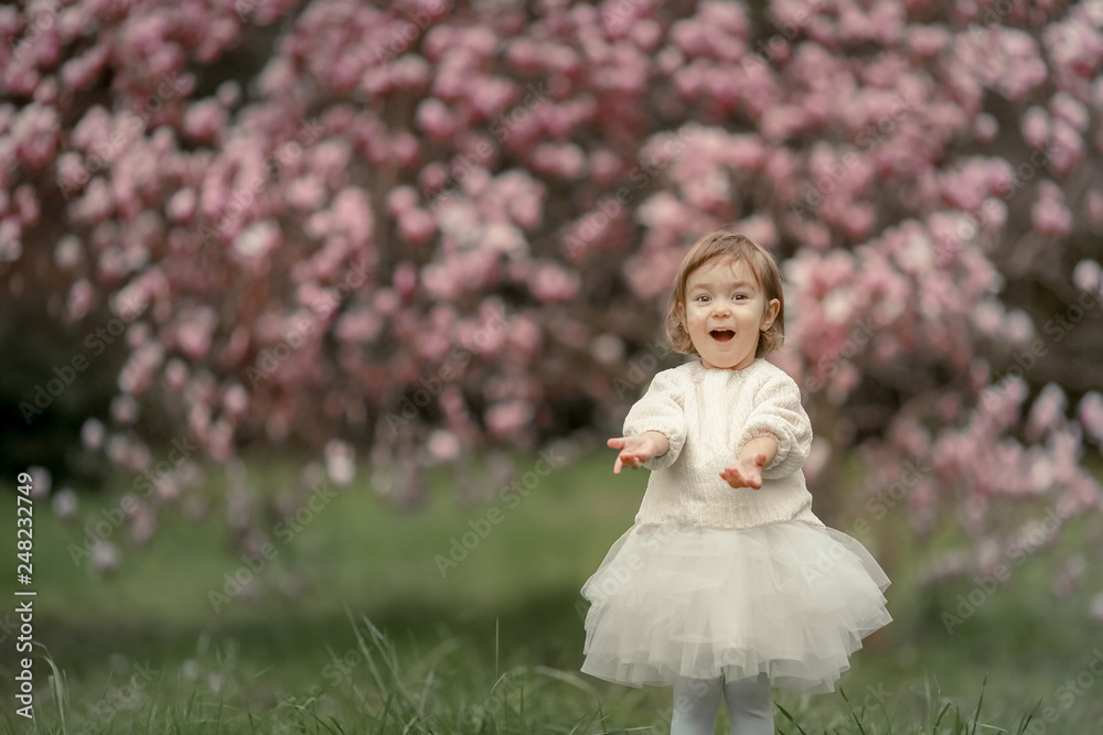 Portrait of happy joyful child in white clothes over tree flowers blossom background. Family playing together outside. Mom cheerfully hold little daughter Newborn spring concept Portrait of happy joyful child in white clothes over tree flowers blossom background. Family playing together outside. Mom cheerfully hold little daughter Newborn spring concept