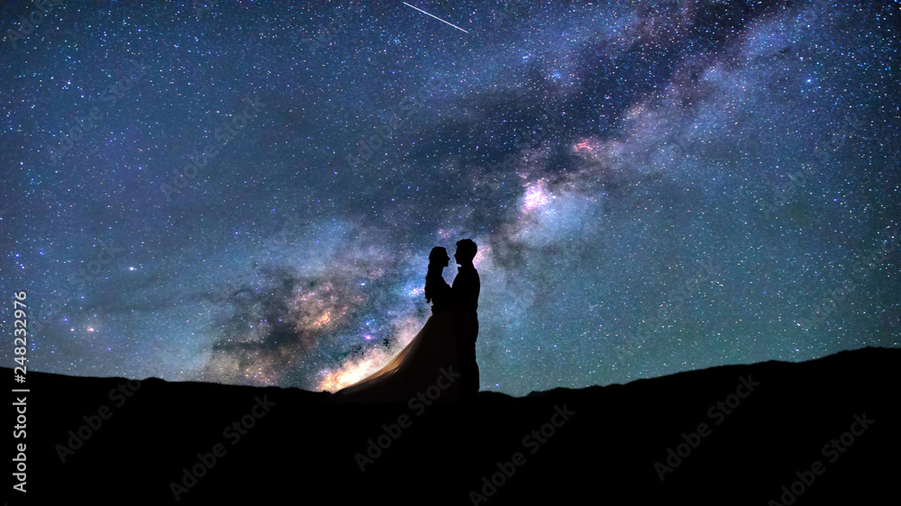 Silhouette of young couple on a milky way stars background. Valentine's day concept. 