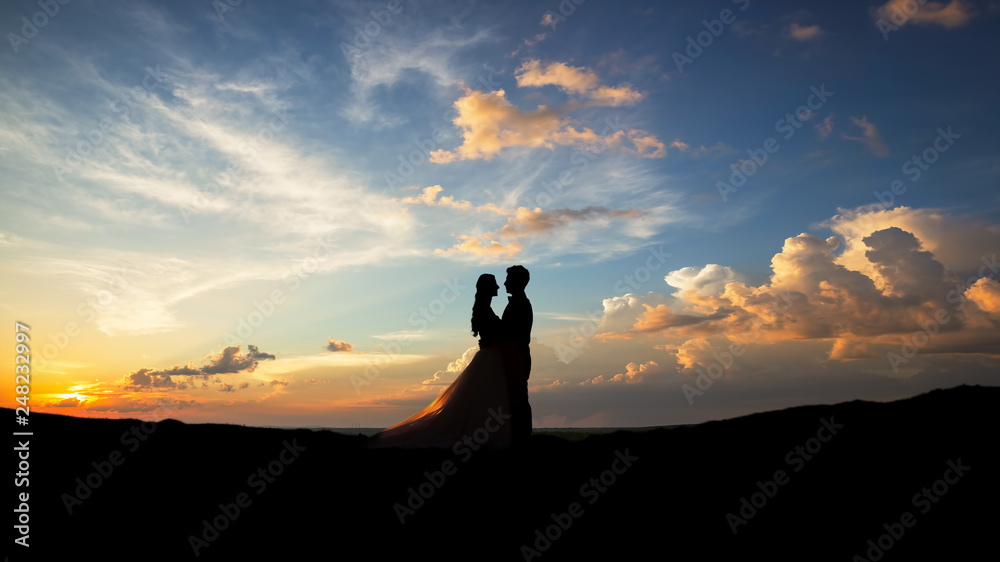 Silhouette of young married couple at sunset.Valentine's day concept.
