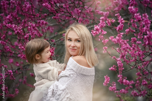 young mother with adorable daughter in park with blossom tree. Happy mother and child.