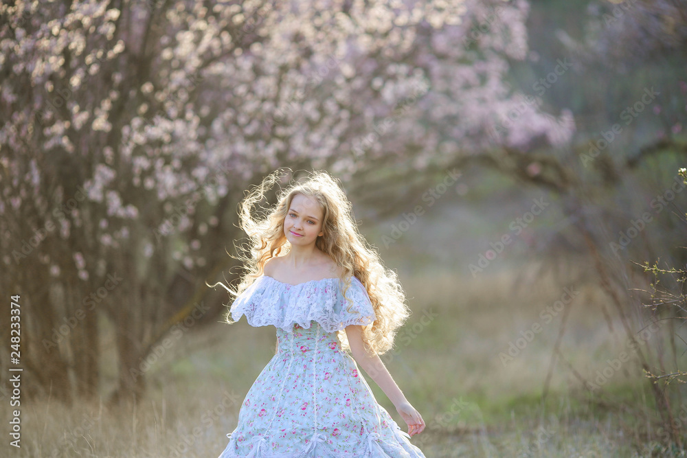 Sweet woman in a beautiful dress, walking through the park with flowers in hands Sweet woman in a beautiful dress, walking through the park with flowers in hands