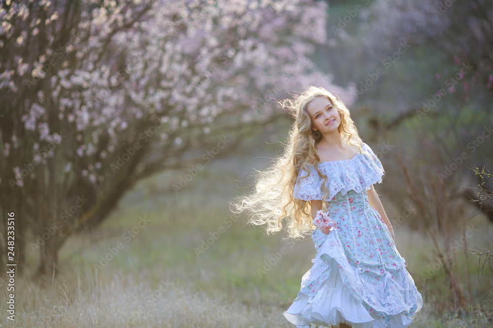 Sweet woman in a beautiful dress dancing in a park with long hair