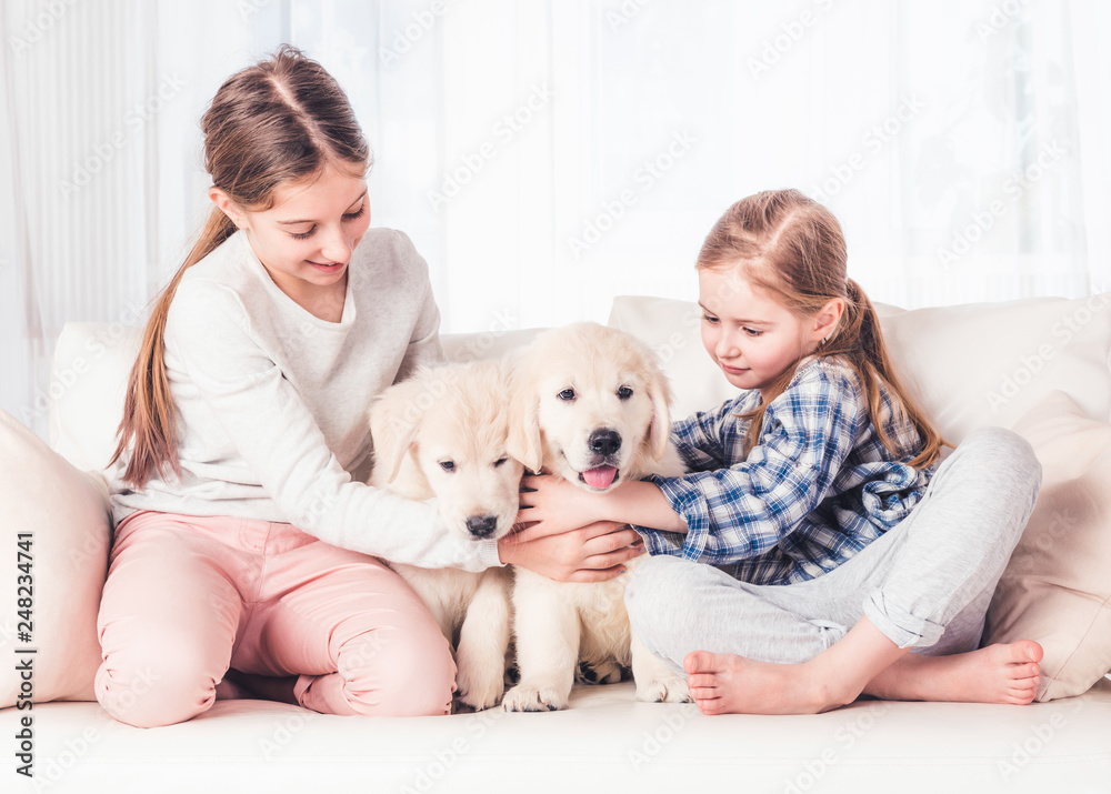 Smiling sisters sitting with puppies