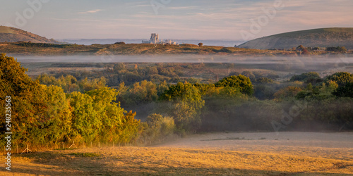 Beautiful morning mist over fields and castle ruin